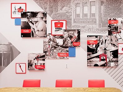 REED Manufacturing conference room feature wall with 3D collage art and red chairs at wooden table