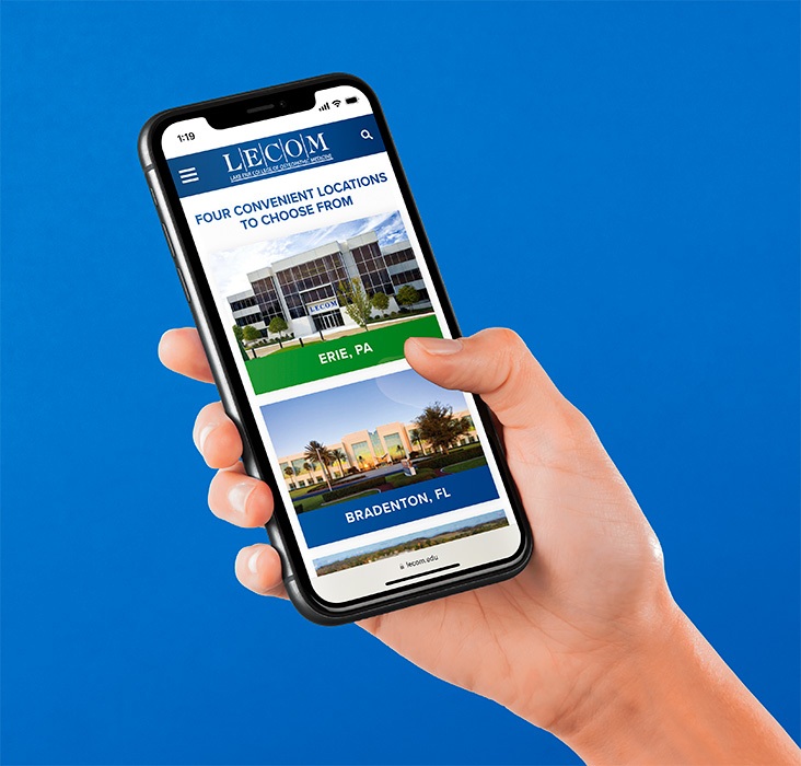 Hand holding iPhone displaying LECOM website button hover.